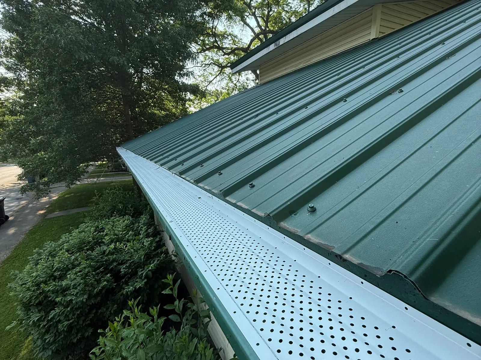 Close-up of a green seamless steel gutter fitted with leaf-guard protection