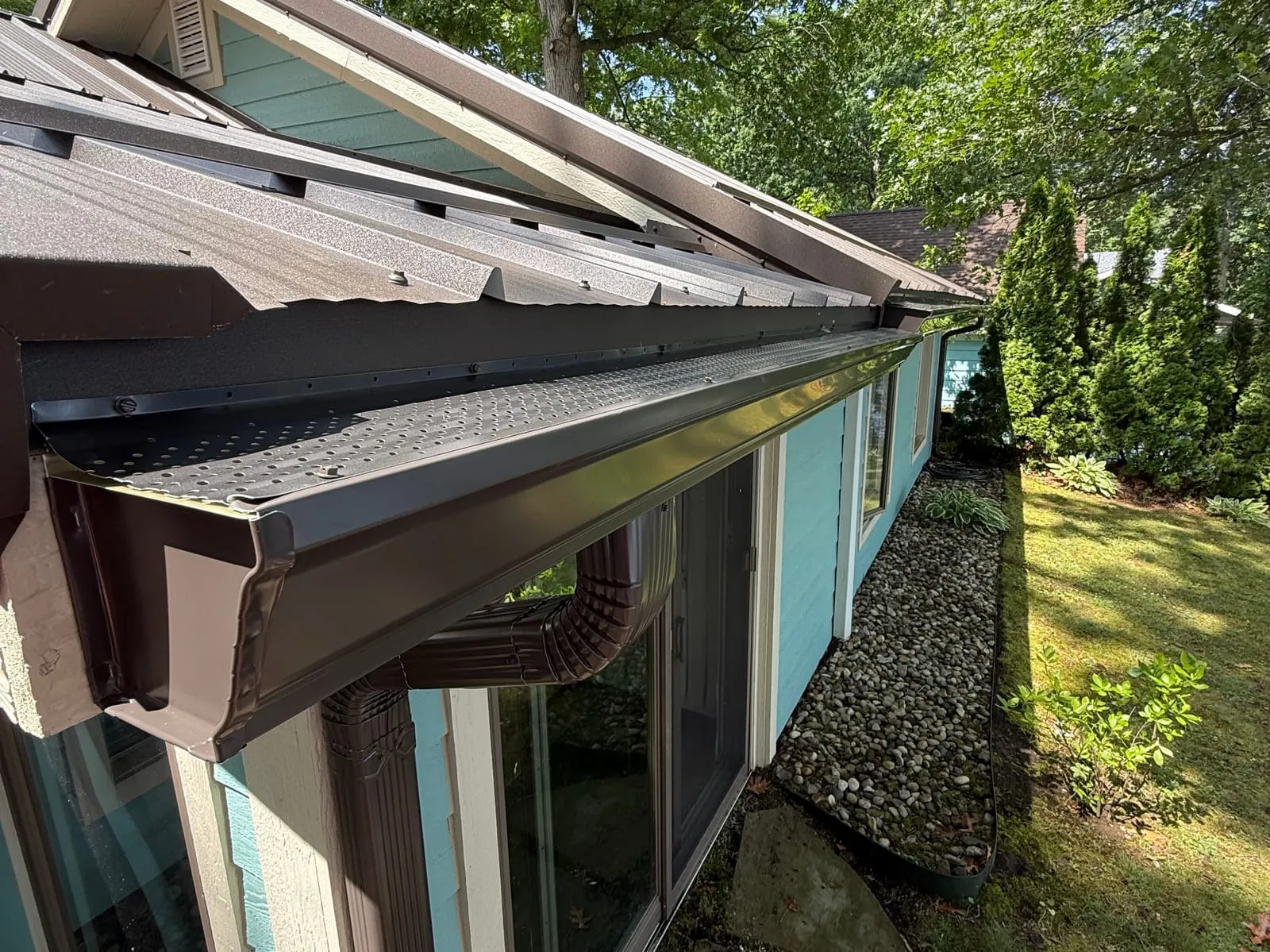 Bronze seamless gutter run along the eave of a home with a metal roof