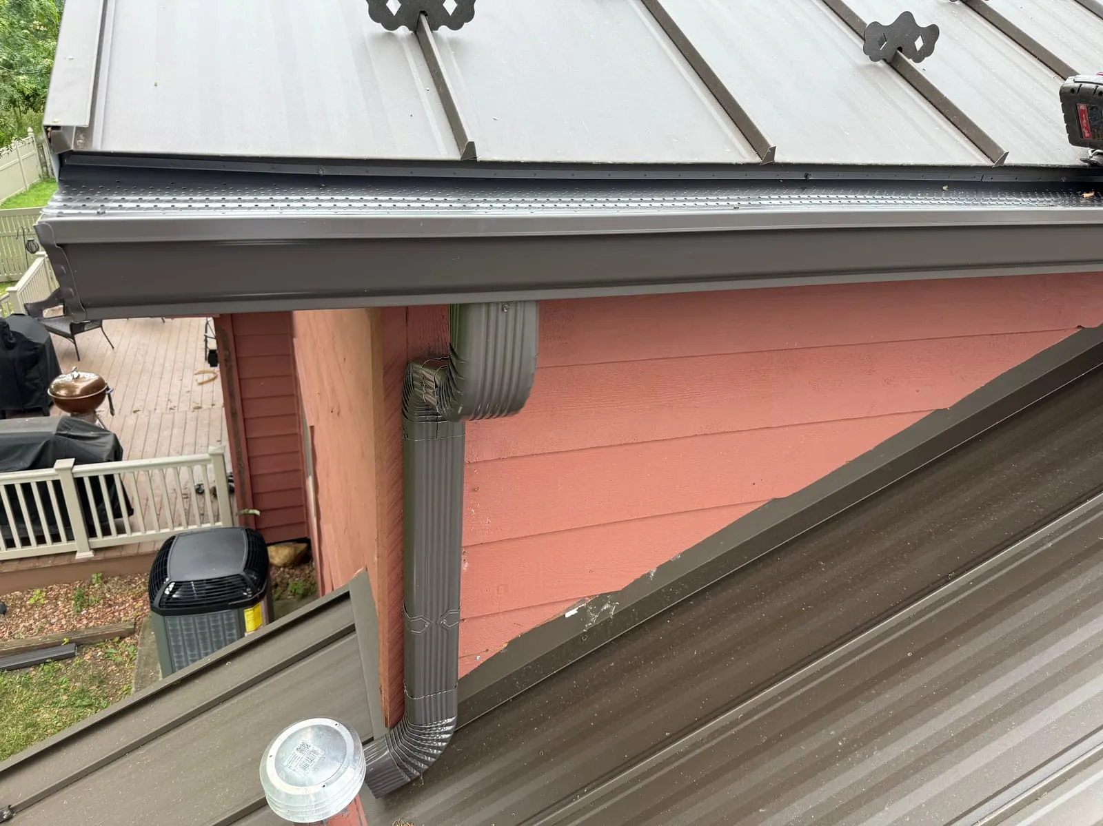 White seamless gutter and downspout on a home with a dark metal roof